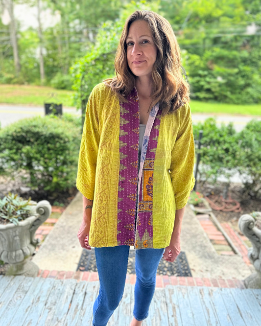 Woman wearing a handcrafted, upcycled Kantha kimono from TheNickStitch, featuring a Citron base with magenta and multicolor patchwork including elephants, made from recycled cotton saris.